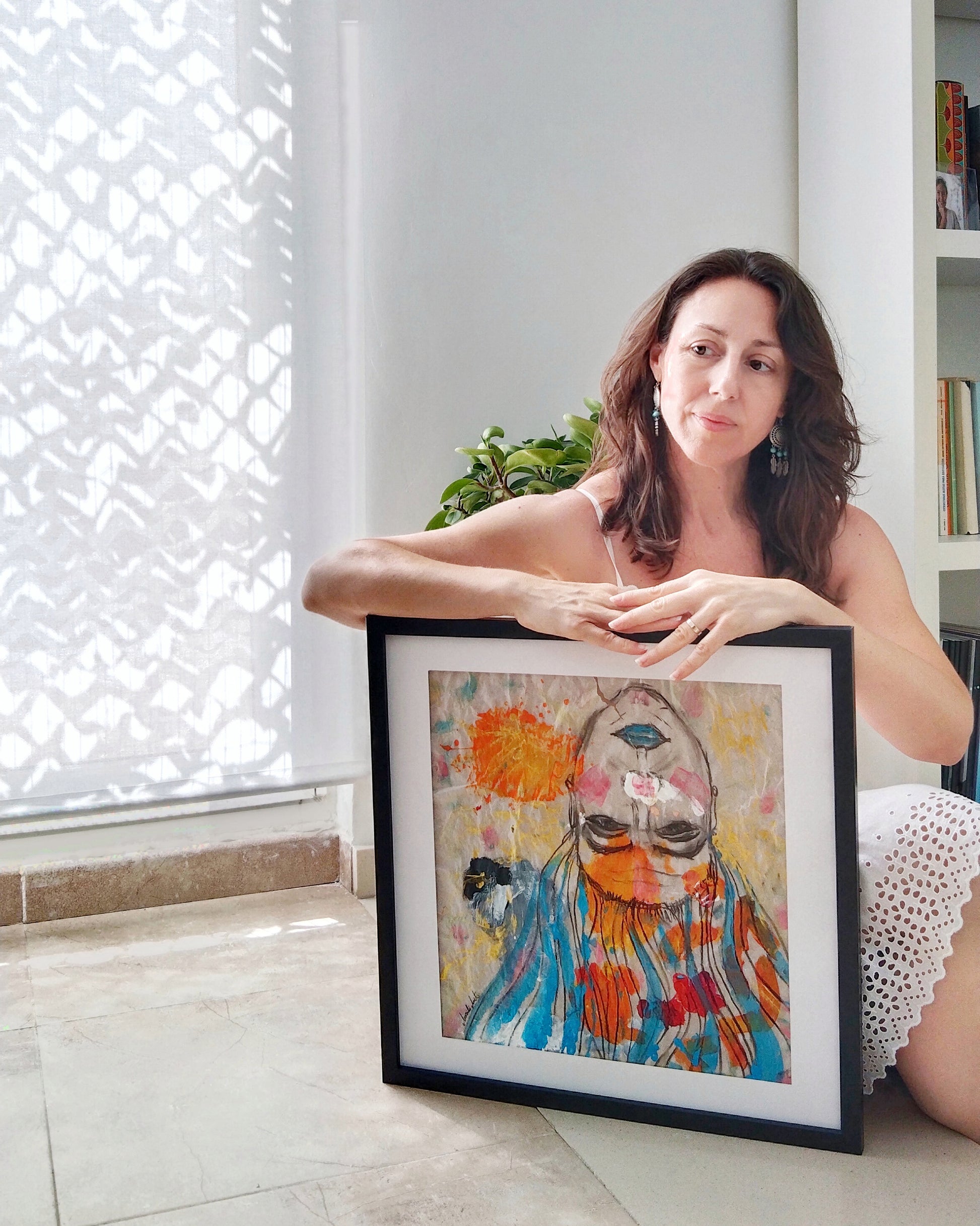 La artista posando junto a su obra "Cargas" Se observa la frescura y perfección de la obra dentro de un espacio luminoso y natural.